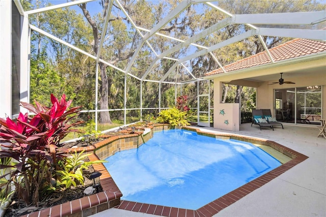 outdoor pool featuring a ceiling fan, glass enclosure, and a patio