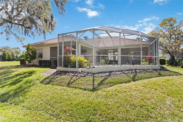 back of house with a yard, a lanai, and stucco siding