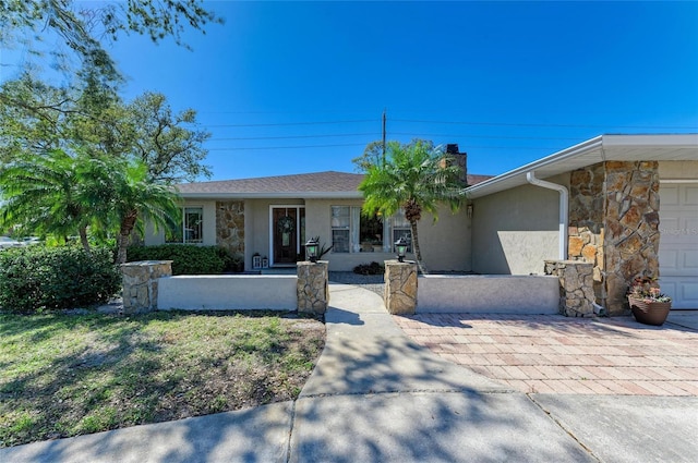 view of front of property with stone siding, stucco siding, an attached garage, and a chimney