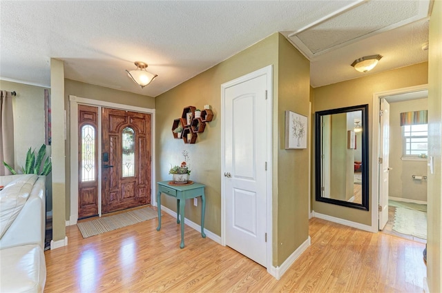 foyer featuring baseboards, light wood-style floors, and a textured ceiling