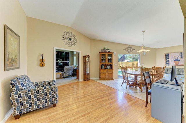 living room featuring lofted ceiling, a notable chandelier, baseboards, and light wood finished floors