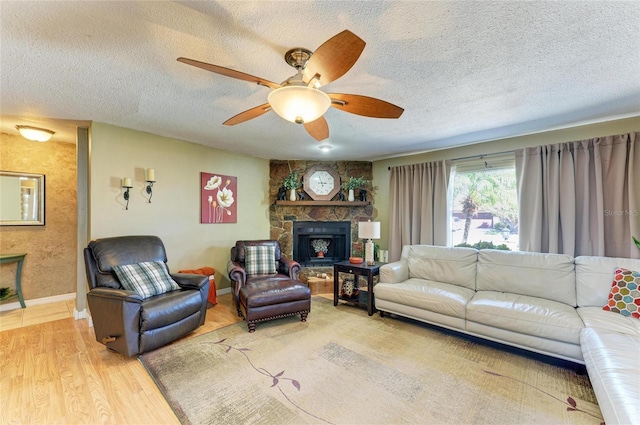 living area featuring ceiling fan, light wood-style flooring, baseboards, and a textured ceiling