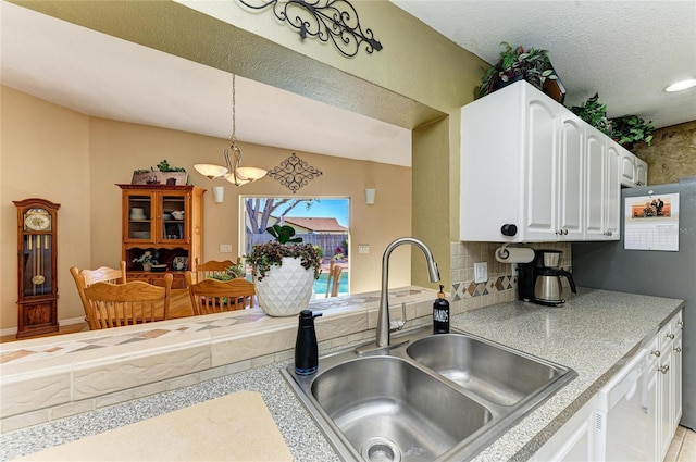 kitchen with white cabinets, dishwasher, light countertops, and a sink