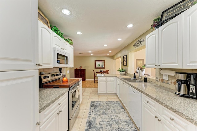 kitchen featuring tasteful backsplash, white cabinets, white appliances, and a sink