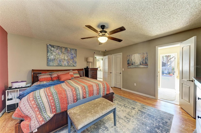 bedroom with light wood-type flooring, baseboards, a textured ceiling, and ceiling fan