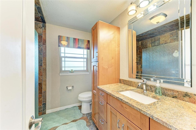 bathroom with vanity, baseboards, a shower, a textured ceiling, and toilet