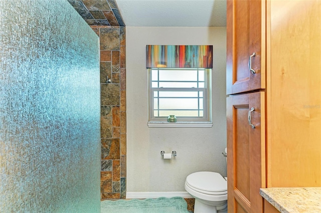 full bathroom featuring toilet, baseboards, and tiled shower