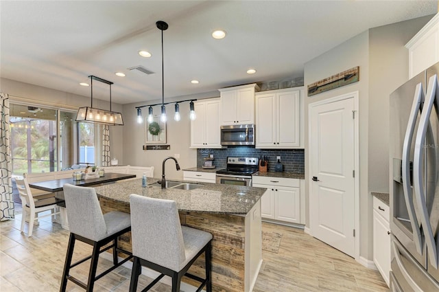 kitchen with tasteful backsplash, visible vents, white cabinets, appliances with stainless steel finishes, and a sink