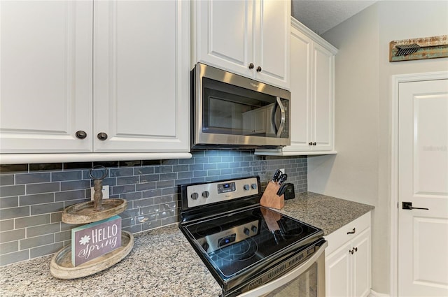 kitchen with tasteful backsplash, white cabinetry, stainless steel appliances, and light stone counters