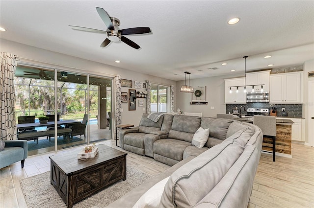 living area featuring ceiling fan, light wood finished floors, and recessed lighting