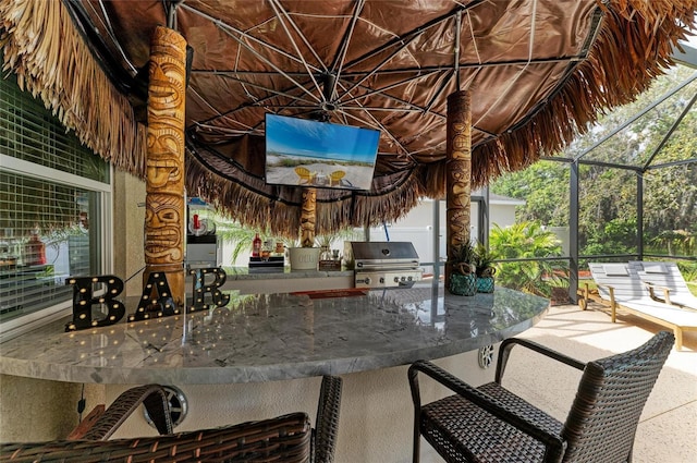 view of patio / terrace with outdoor wet bar, glass enclosure, a grill, and exterior kitchen