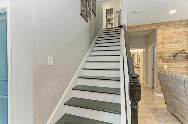 stairs with baseboards, wood tiled floor, and wooden walls