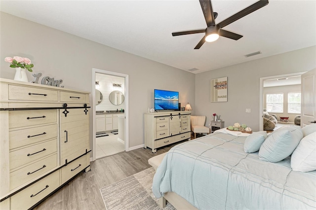 bedroom with a ceiling fan, visible vents, light wood-style flooring, and ensuite bath