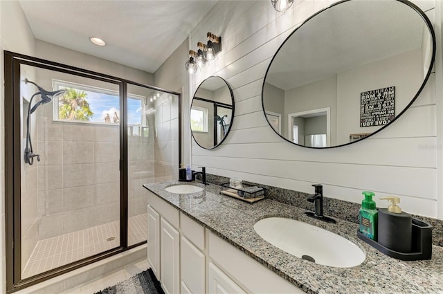 full bath featuring double vanity, a stall shower, and a sink