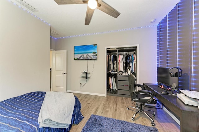 bedroom featuring wood finished floors, a ceiling fan, visible vents, baseboards, and a closet