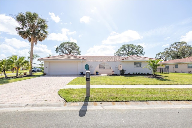 view of front of property featuring decorative driveway, an attached garage, a tiled roof, and a front lawn