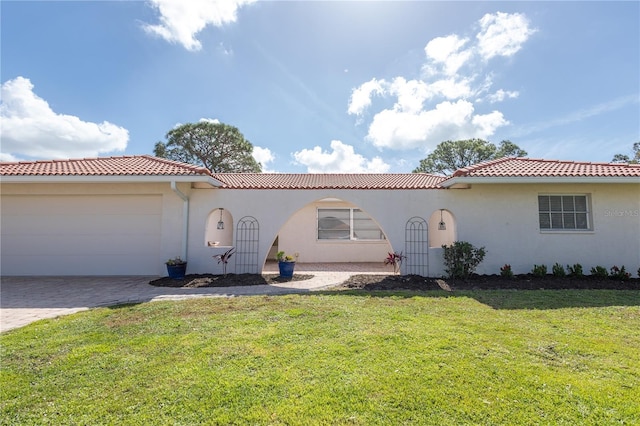 mediterranean / spanish-style house with a garage, a tiled roof, decorative driveway, stucco siding, and a front yard