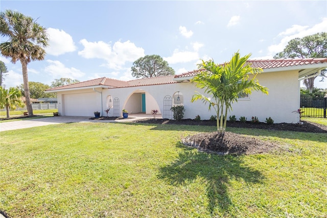 mediterranean / spanish-style home with a tiled roof, an attached garage, fence, a front lawn, and stucco siding