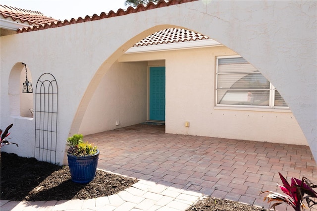 exterior space with a patio area, a tiled roof, and stucco siding