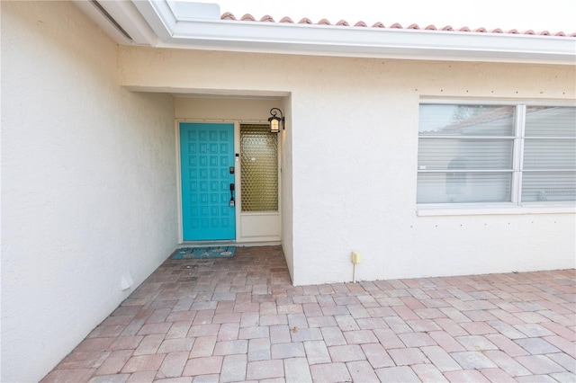 property entrance with a tile roof and stucco siding