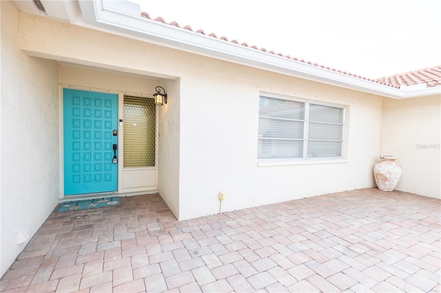 entrance to property featuring a tiled roof and stucco siding