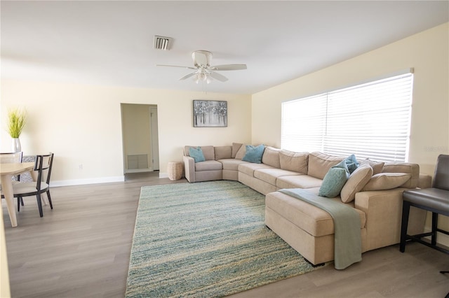 living area featuring light wood-style floors, baseboards, visible vents, and a ceiling fan