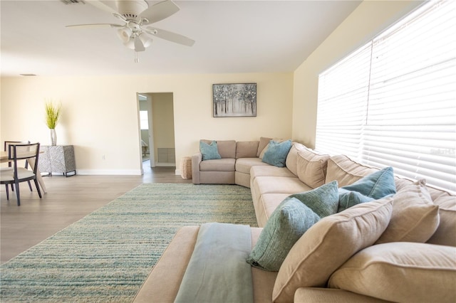 living room featuring ceiling fan, baseboards, and wood finished floors