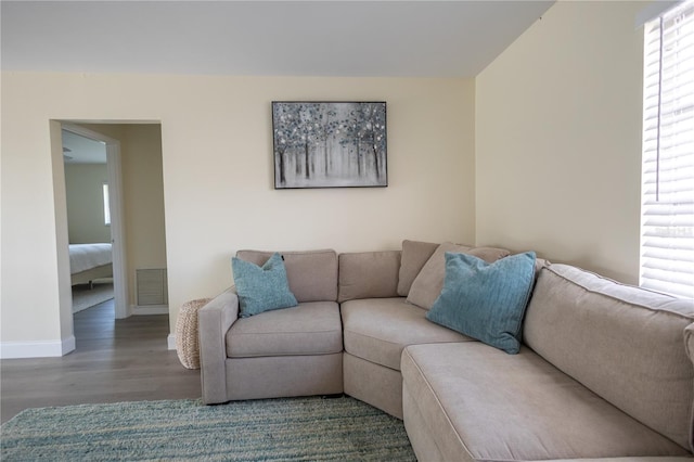 living room with wood finished floors, visible vents, and baseboards