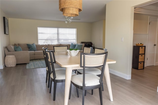 dining room featuring light wood-style floors, a wainscoted wall, and a ceiling fan