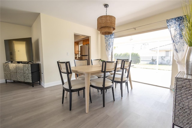 dining room with a notable chandelier, baseboards, and wood finished floors