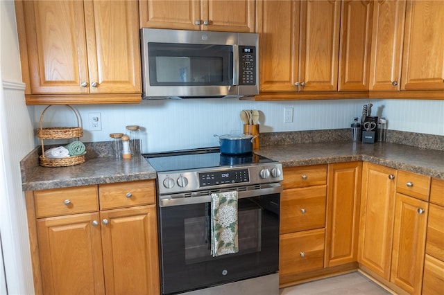 kitchen featuring dark countertops, appliances with stainless steel finishes, and brown cabinets