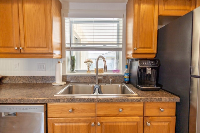 kitchen with stainless steel appliances, dark countertops, brown cabinets, and a sink