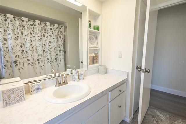 bathroom featuring curtained shower, vanity, and baseboards