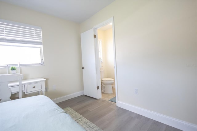 bedroom featuring ensuite bath, baseboards, and wood finished floors