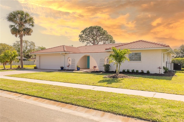 mediterranean / spanish-style home featuring a front lawn, an attached garage, and a tile roof