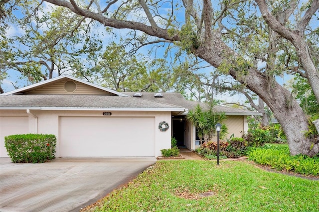 ranch-style home with a front yard, driveway, an attached garage, and stucco siding