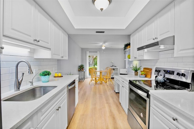 kitchen featuring a raised ceiling, visible vents, appliances with stainless steel finishes, a sink, and under cabinet range hood