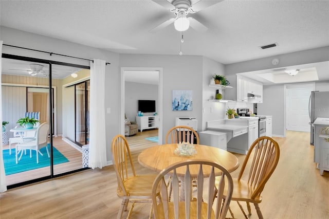 dining space featuring light wood-style floors, ceiling fan, and a textured ceiling