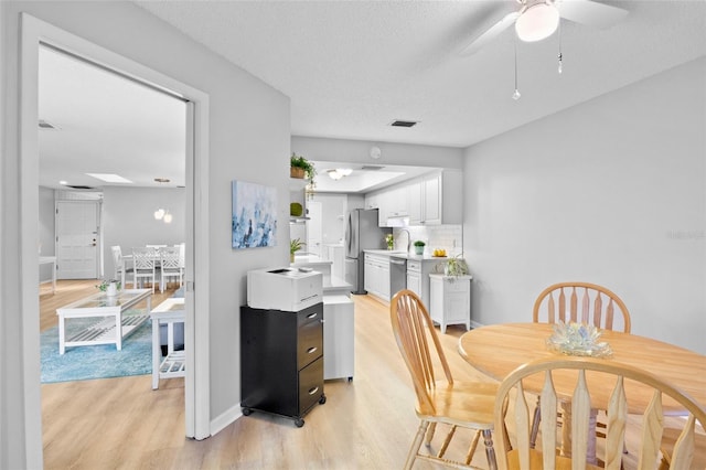 dining area with visible vents, light wood-style flooring, and a textured ceiling