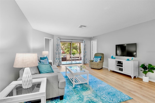 living area featuring light wood-style floors, visible vents, and baseboards