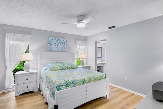 bedroom featuring light wood finished floors, visible vents, ceiling fan, a textured ceiling, and baseboards