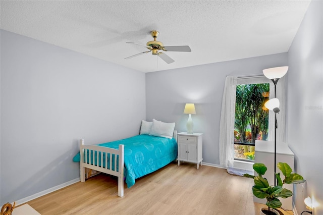 bedroom featuring a ceiling fan, a textured ceiling, baseboards, and wood finished floors