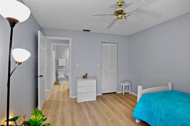 bedroom featuring light wood-style flooring, a textured ceiling, visible vents, and baseboards