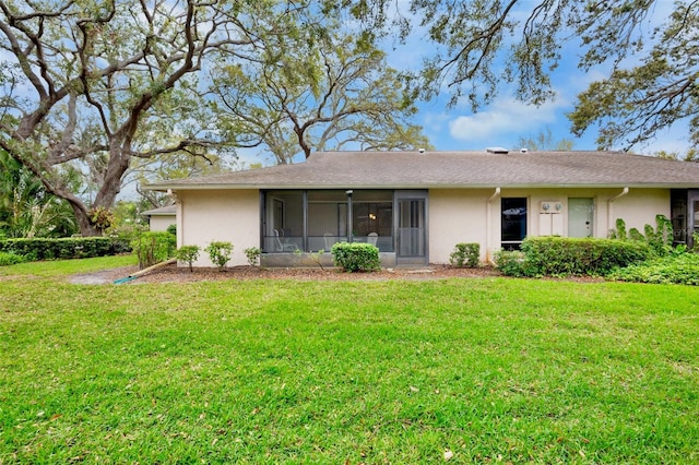 back of property with stucco siding and a yard