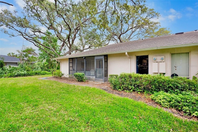 exterior space featuring a front lawn, a shingled roof, a sunroom, and stucco siding