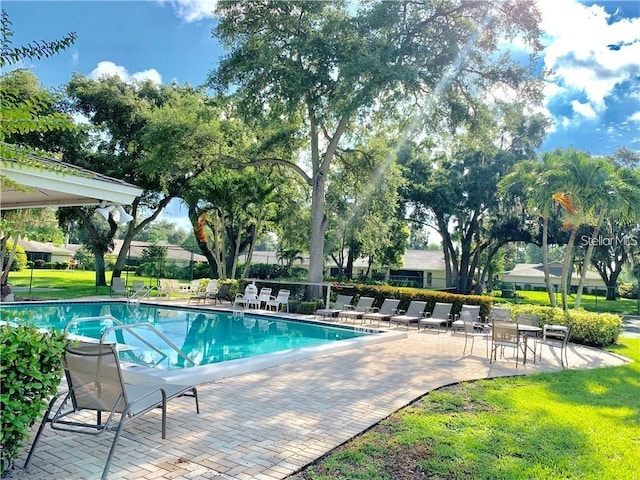 community pool featuring a patio area, fence, and a yard