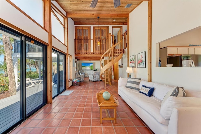 living area with visible vents, a towering ceiling, wood ceiling, stairway, and tile patterned flooring