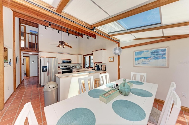 dining area with a ceiling fan, a towering ceiling, and light tile patterned floors