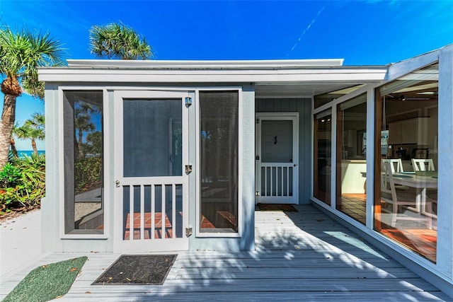 view of exterior entry with board and batten siding and a wooden deck