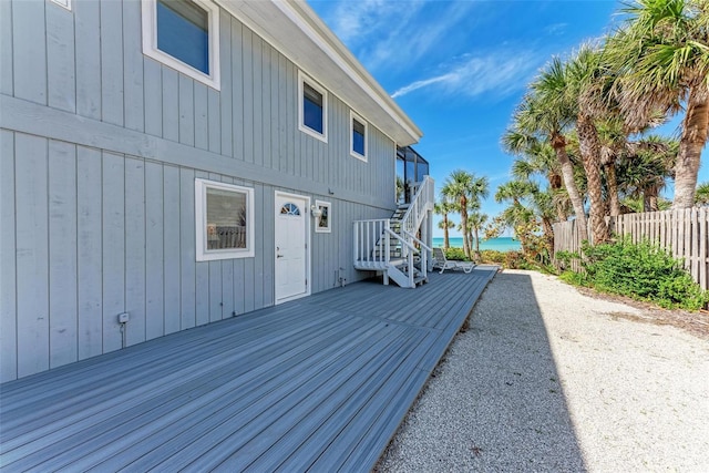 wooden terrace featuring a water view, stairs, and fence